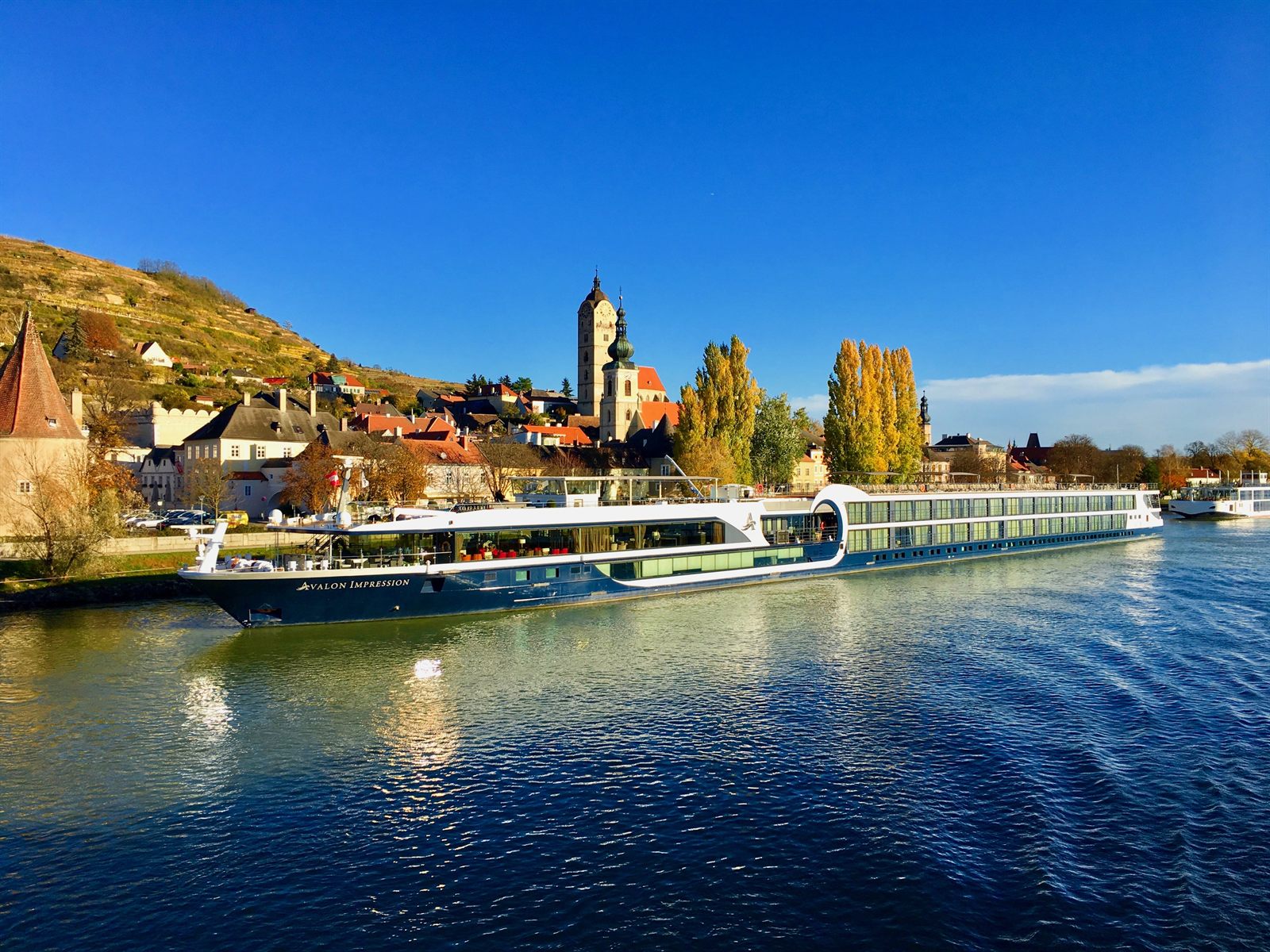 River cruise ship moored below a village and church in the Wachau Valley on the Danube